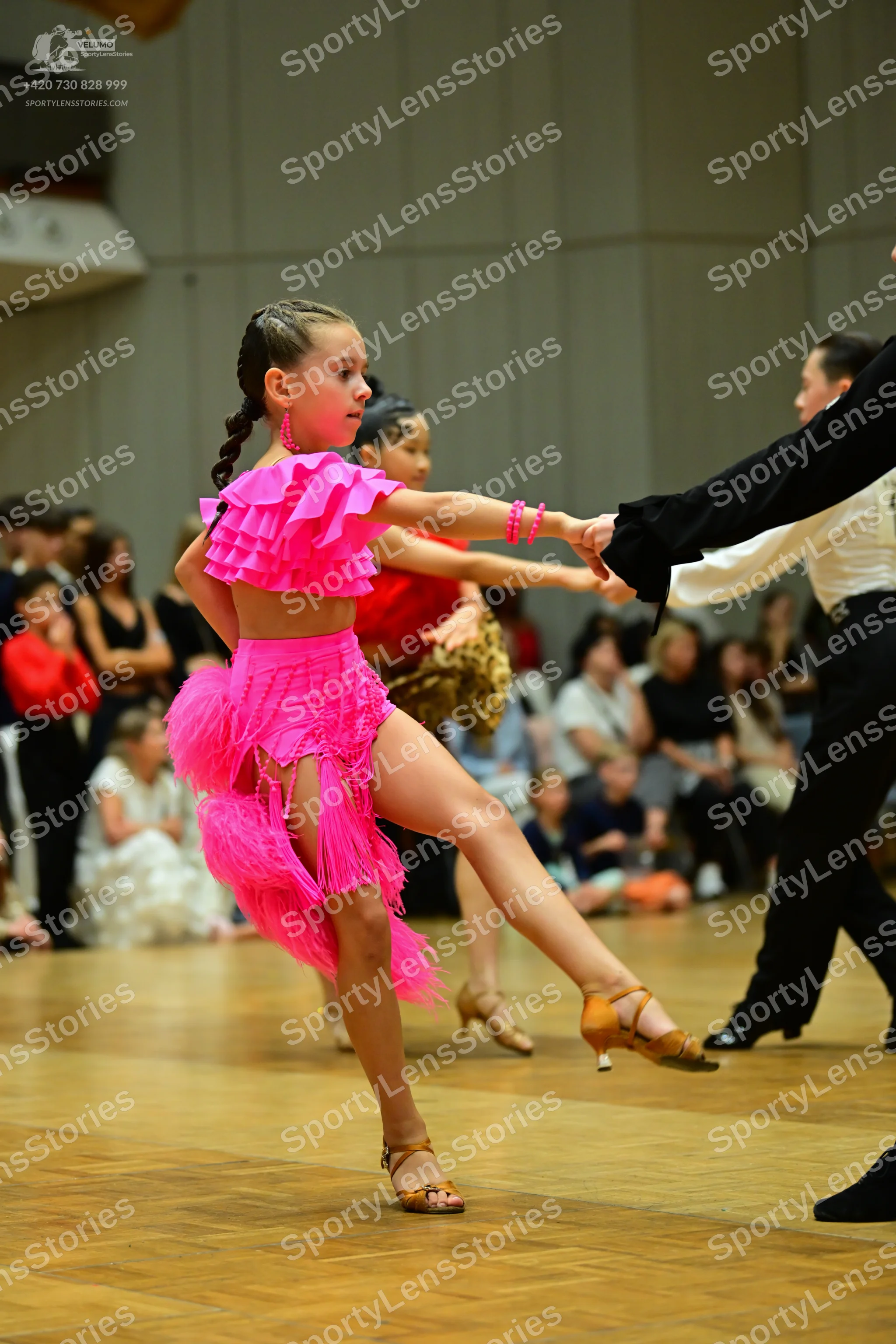 Dancesport competitor: Female dancer: bright pink latin dance costume featuring a ruffled top and a lon