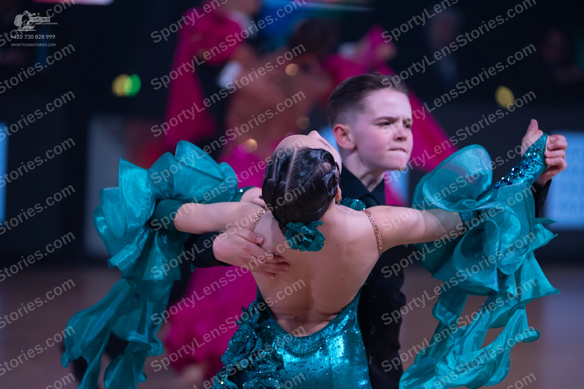 Dancesport competitor: Female dancer: teal sequin latin dress with large, voluminous ruffles on the sle