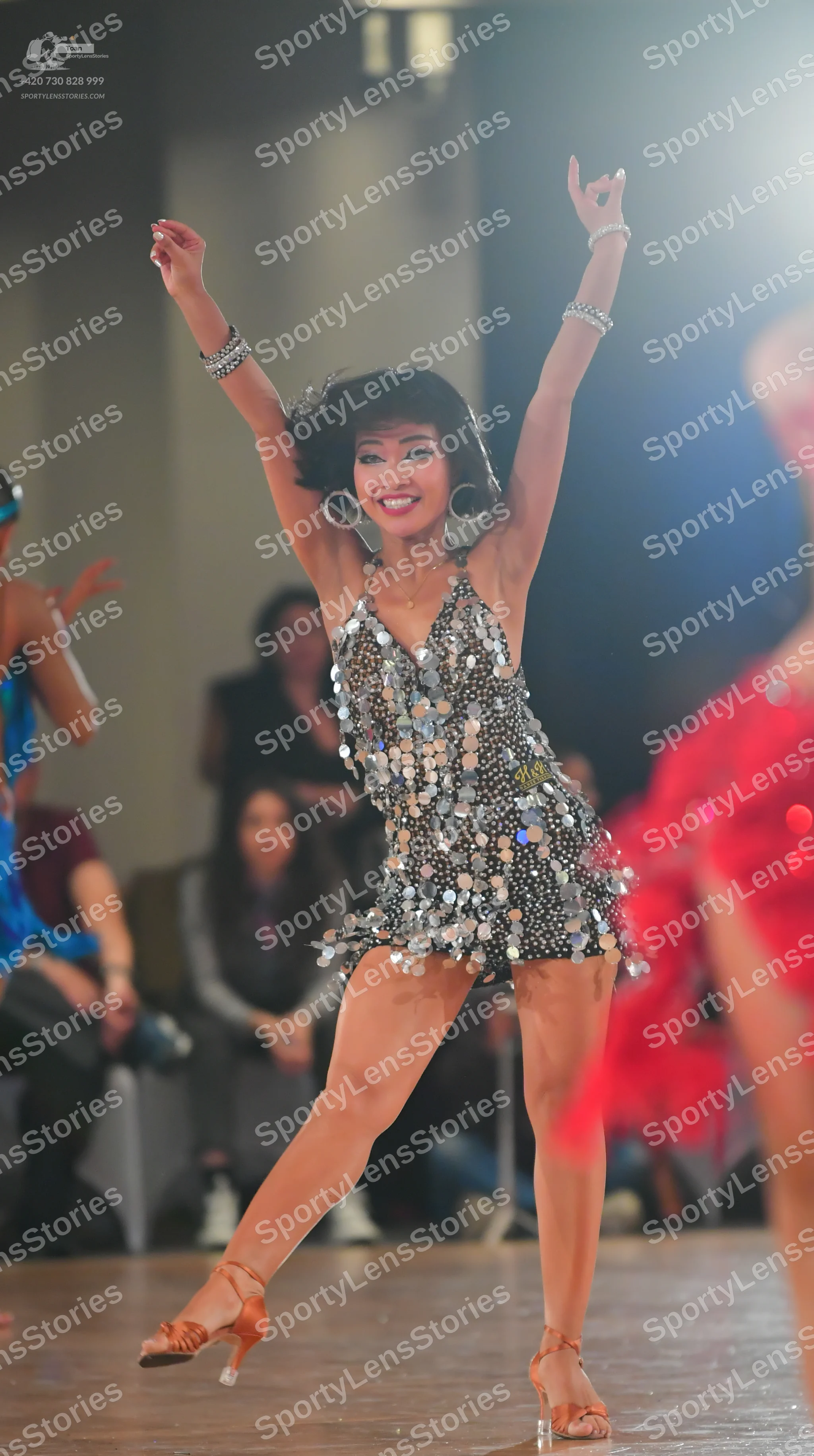Dancesport competitor: Central female dancer: silver, sleeveless Latin dance dress heavily embellished