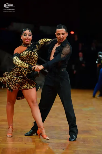 Dancesport competitor: Female dancer: leopard print Latin dress with long sleeves and black sequin embe