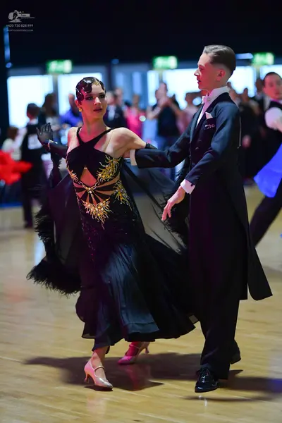 Dancesport competitor: Female dancer: black ballroom dress with a gold sequined bodice, black feather t