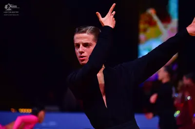 Dancesport competitor: Male dancer: black long-sleeved top with a deep V-neck and black trousers