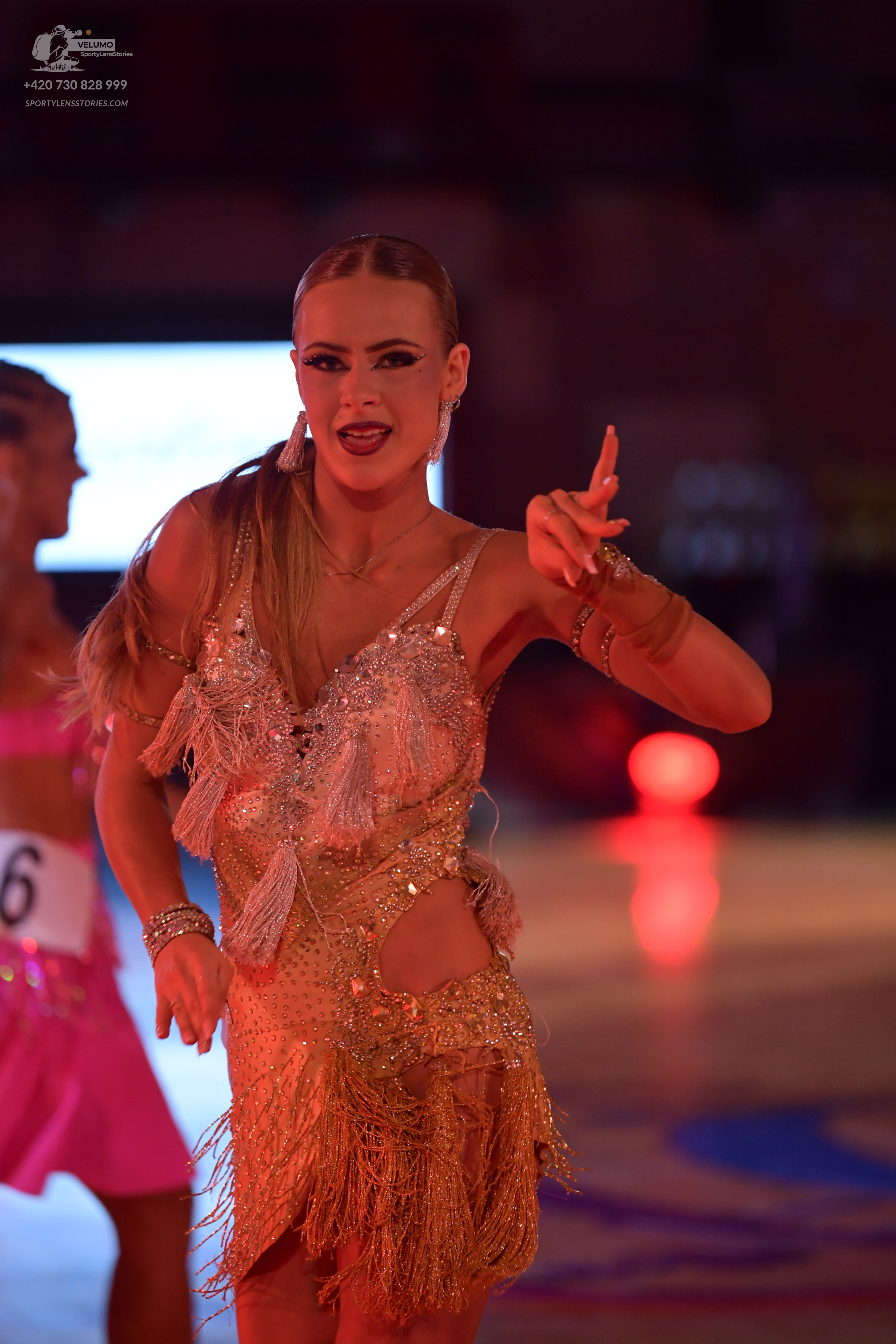 Dancesport competitor: Female dancer (foreground): gold Latin dance dress with sequins and fringe