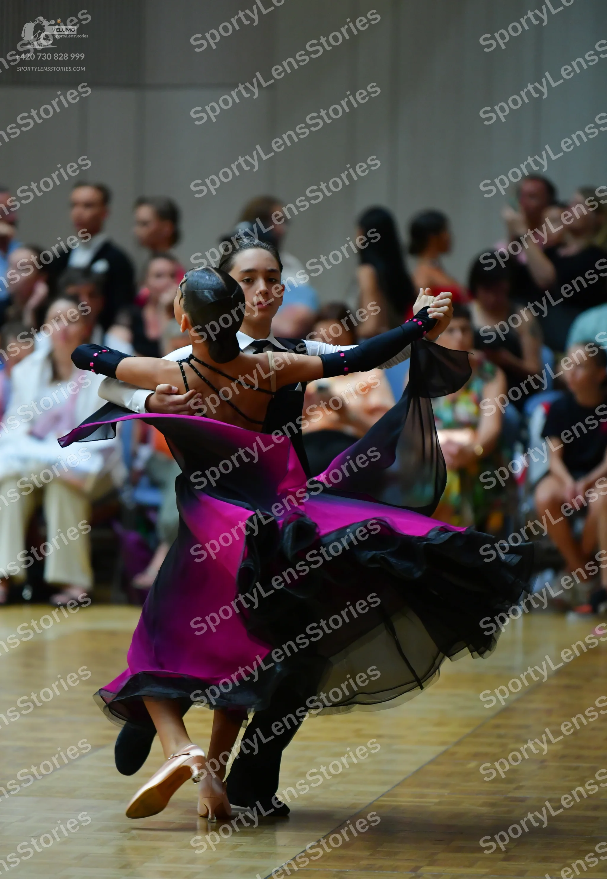 Dancesport competitor: Female dancer: magenta and black ballgown with a voluminous, layered skirt and a