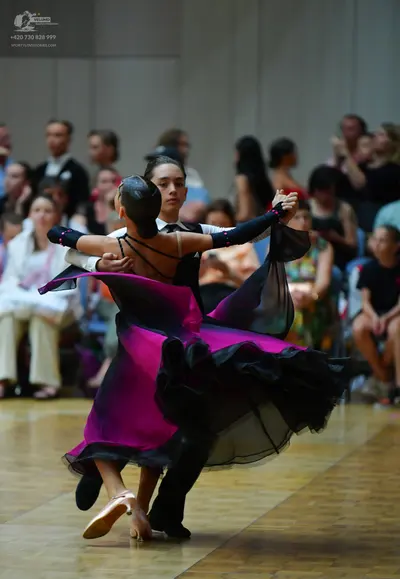 Dancesport competitor: Female dancer: magenta and black ballgown with a voluminous, layered skirt and a