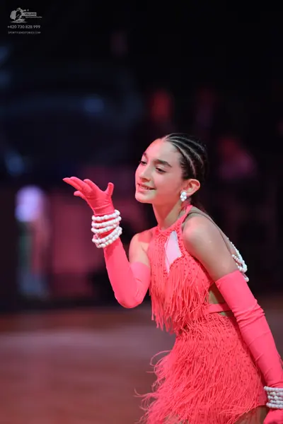 Dancesport competitor: Female dancer: bright pink latin dress with fringe, matching long pink gloves, a