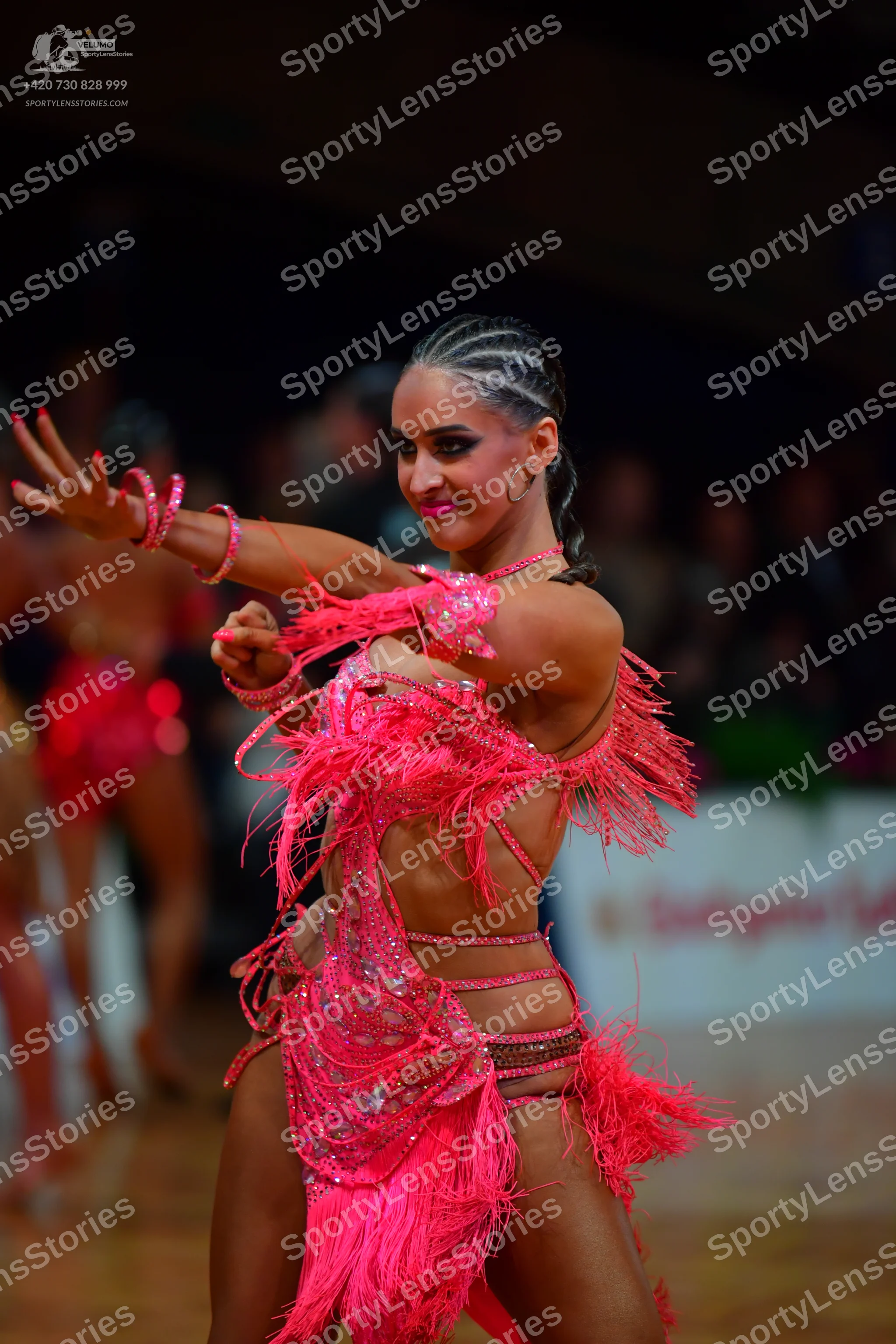 Dancesport competitor: Female dancer (foreground): bright pink Latin dance dress featuring long fringe,