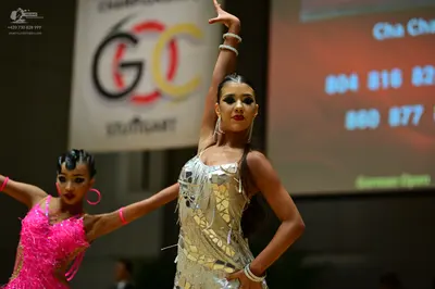 Dancesport competitor: Female dancer on left: bright pink latin dress with sequins and fringe, pink hoo