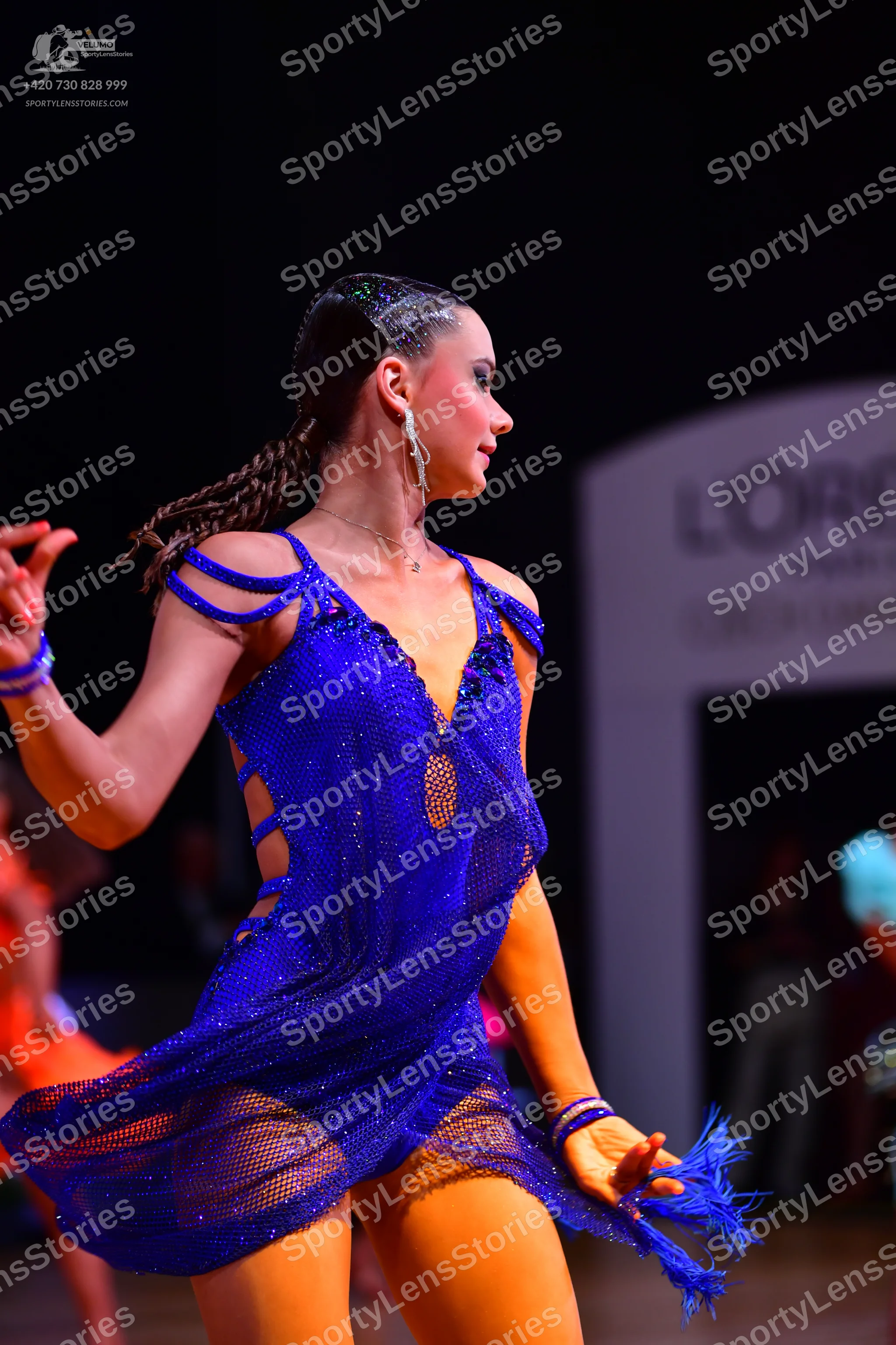 Dancesport competitor: Female dancer: blue Latin dance dress with mesh fabric, cutouts, and fringe at t