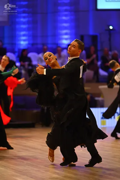 Dancesport competitor: Male dancer: black ballroom suit with a white shirt, black trousers, and black d