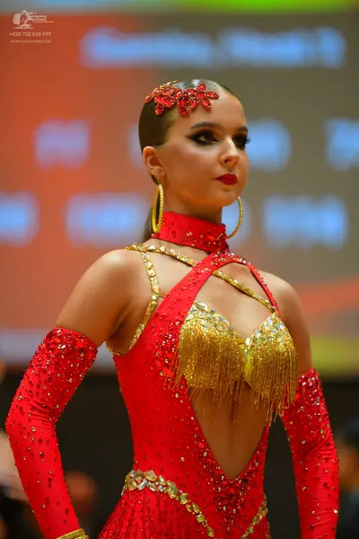 Dancesport competitor: Female dancer: red Latin dress with red sequins, gold fringe, and long sequined 