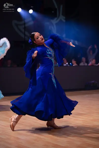 Dancesport competitor: Female dancer: royal blue ballgown with long flowing sleeves and silver sequined