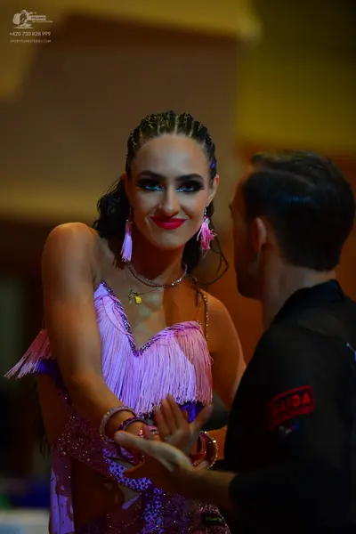 Dancesport competitor: Female dancer: light purple latin dress with fringe and sequins, wearing large p