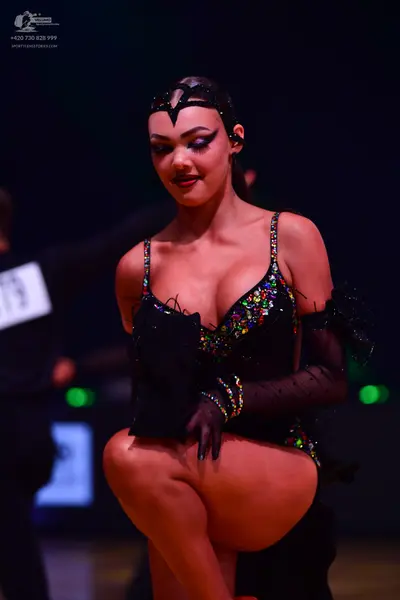 Dancesport competitor: Female dancer: black latin dress with multi-colored sequins and thin straps, wit