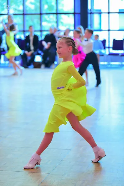Dancesport competitor: Female dancer in foreground: lime green latin dress with long sleeves
