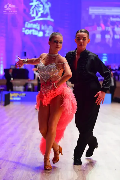 Dancesport competitor: Female dancer: silver sequined Latin bodice with thin straps, bright pink feathe