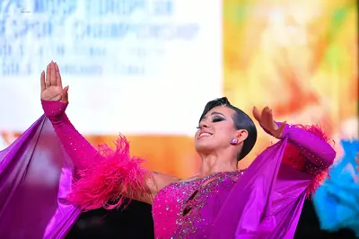 Dancesport competitor: Female dancer: bright pink Latin dress with a sequined bodice, long flowing sati