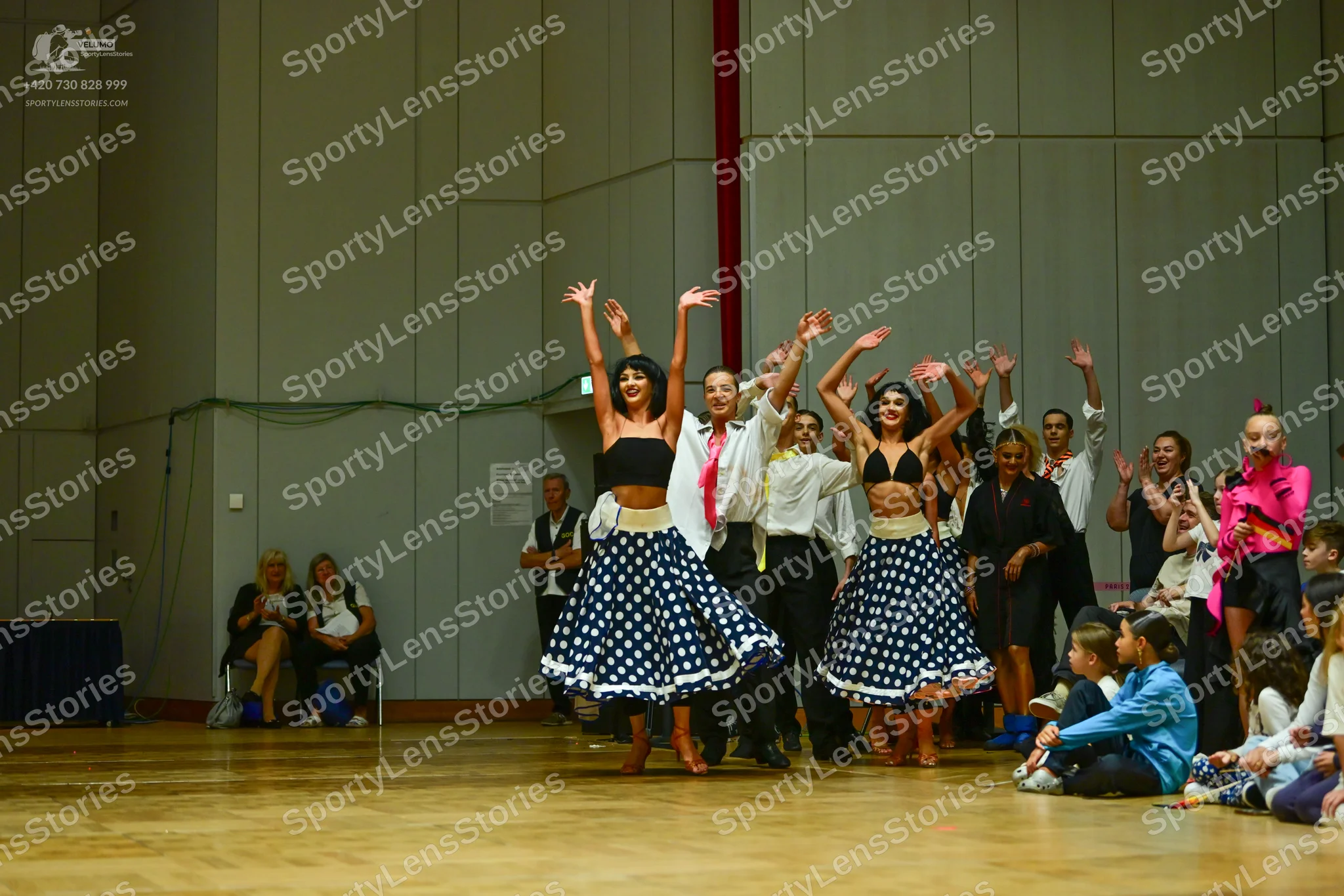 Dancesport competitor: Female dancers: matching black crop tops and large, full, dark blue or black ski