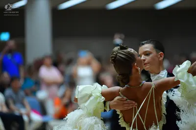 Dancesport competitor: Female dancer: cream-colored ballroom dress with ruffles, lace, and feathery/fri