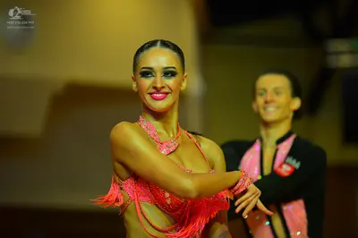 Dancesport competitor: Female dancer: pink/coral Latin dance costume with sequins and fringe