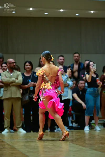 Dancesport competitor: Female dancer: bright pink latin dance dress with a ruffled skirt, featuring yel