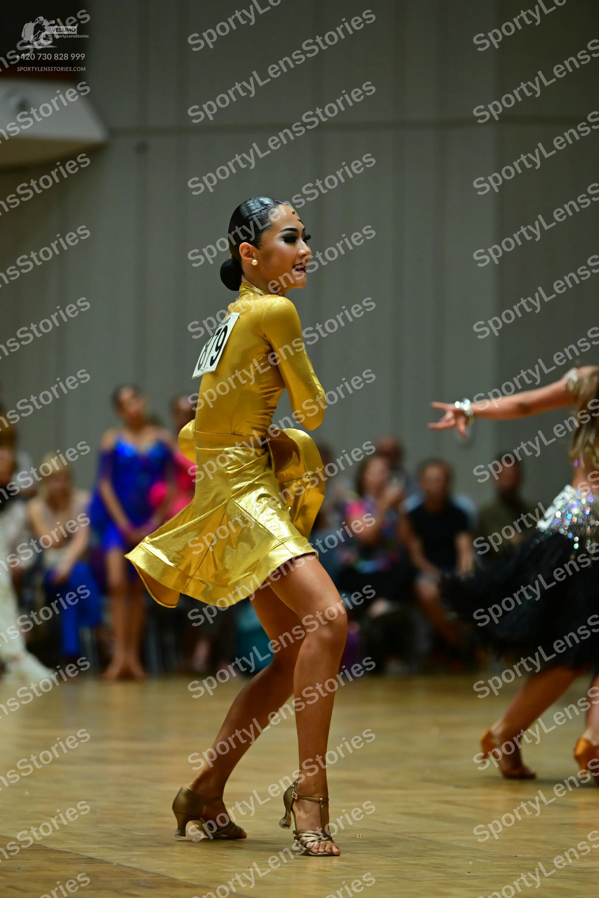 Dancesport competitor #179: Female dancer in center: gold satin latin dress with long sleeves