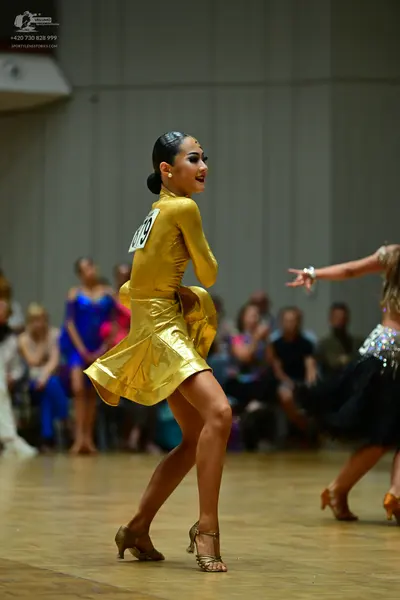 Dancesport competitor #179: Female dancer in center: gold satin latin dress with long sleeves