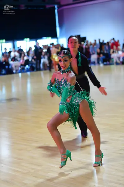 Dancesport competitor: Female dancer: bright green Latin dance dress with sequins and long fringe, matc