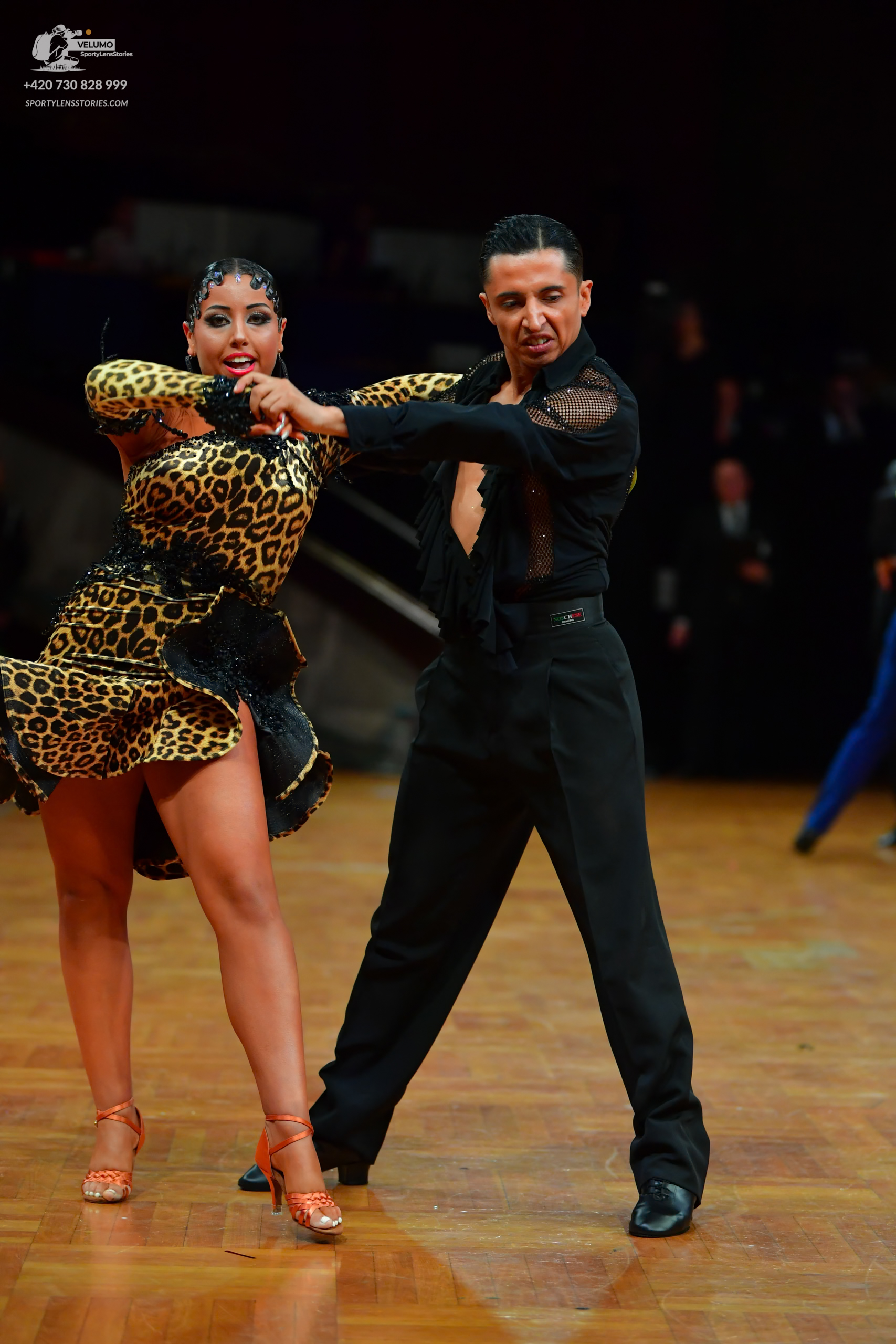 Dancesport competitor: Female dancer: leopard print latin dress with a ruffled skirt and tan strappy he