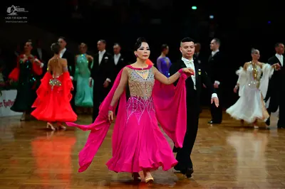 Dancesport competitor: Female dancers: one in a bright pink dress with a sequined/beaded bodice and lon