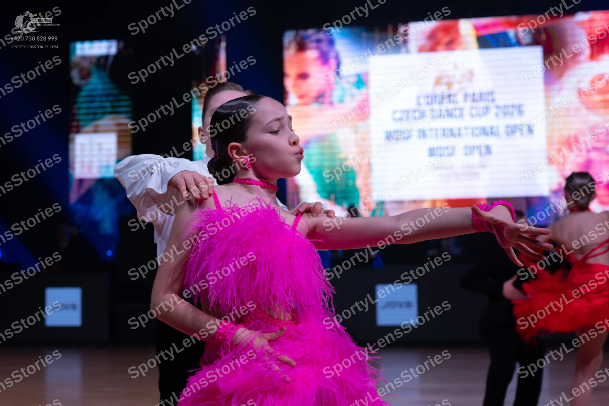 Dancesport competitor: Female dancer: bright pink latin dress with a feathery or heavily fringed textur