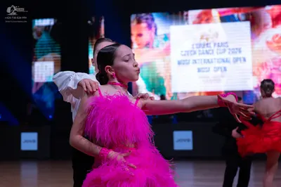 Dancesport competitor: Female dancer: bright pink latin dress with a feathery or heavily fringed textur