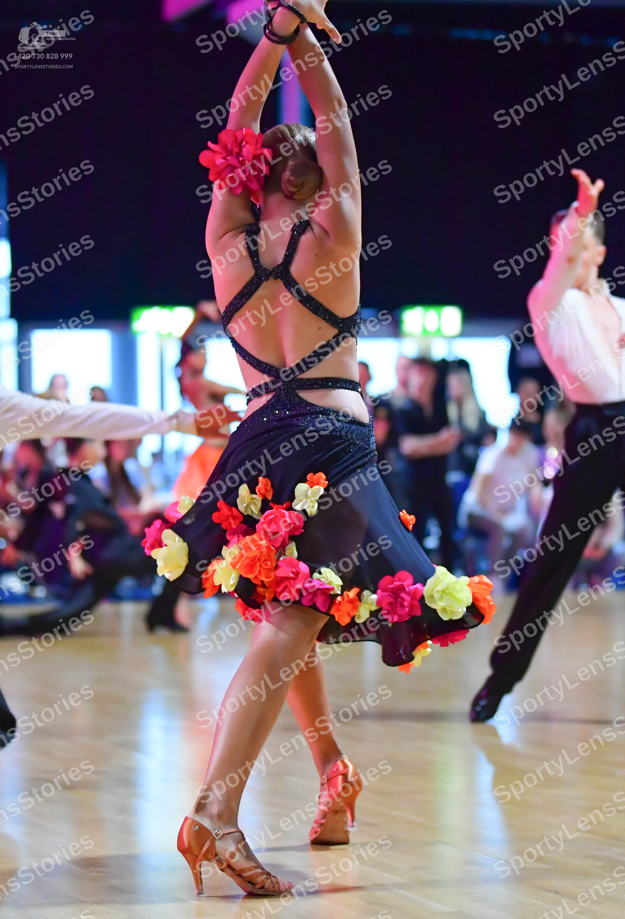 Dancesport competitor: Female dancer: black latin dress with sequined crisscross straps and colorful fa