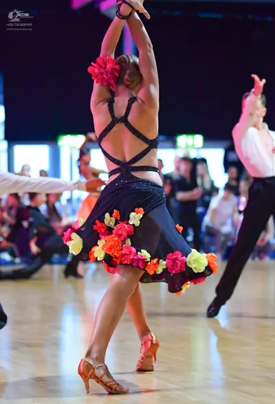 Dancesport competitor: Female dancer: black latin dress with sequined crisscross straps and colorful fa