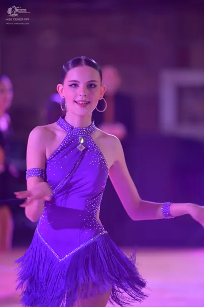 Dancesport competitor: Female dancer: purple latin dress with rhinestones and fringe, matching rhinesto