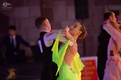 Dancesport competitor: Male dancer in foreground: black dance vest over a white long-sleeved shirt
