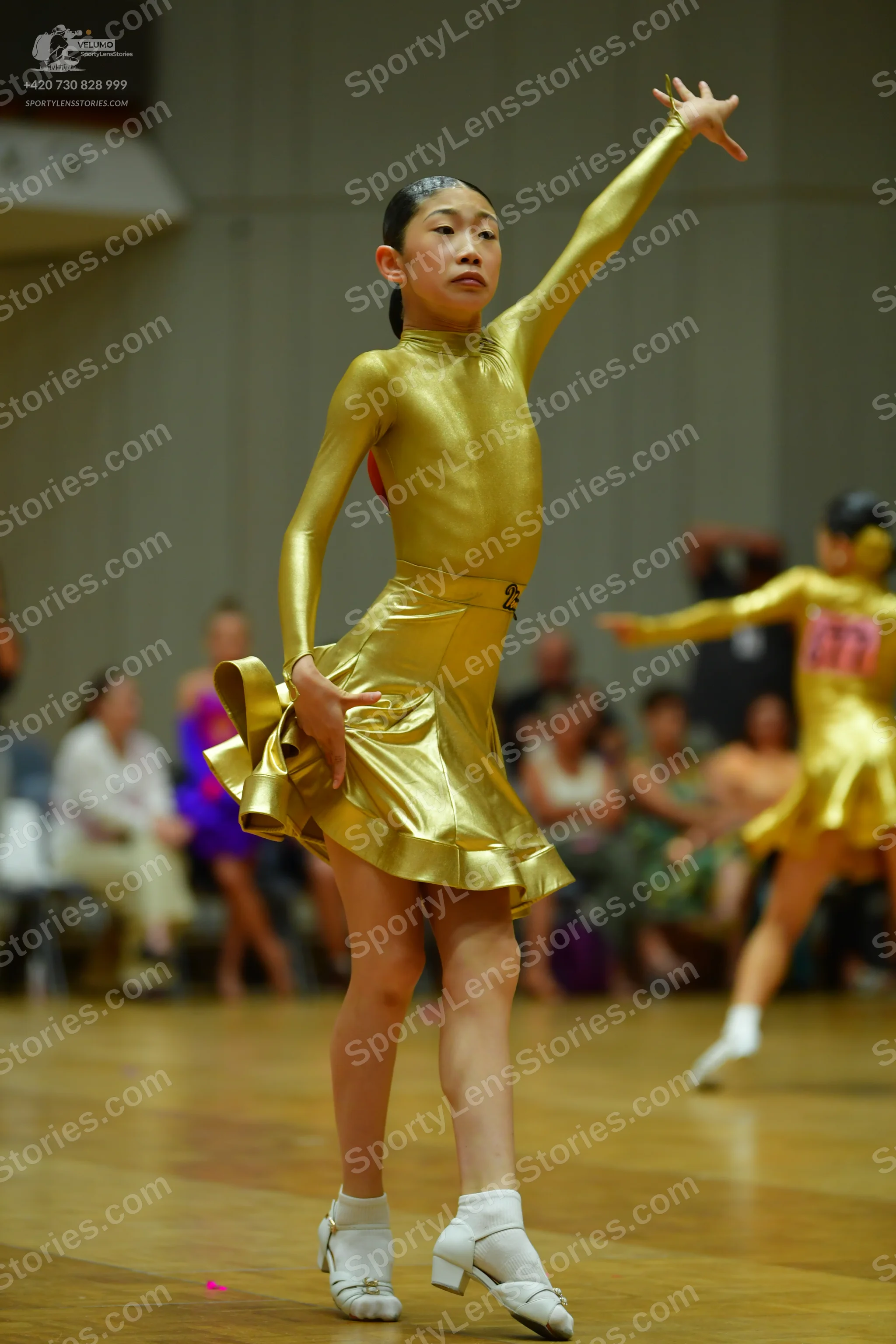 Dancesport competitor: Female dancer: gold metallic long-sleeved Latin dress with a flared skirt
