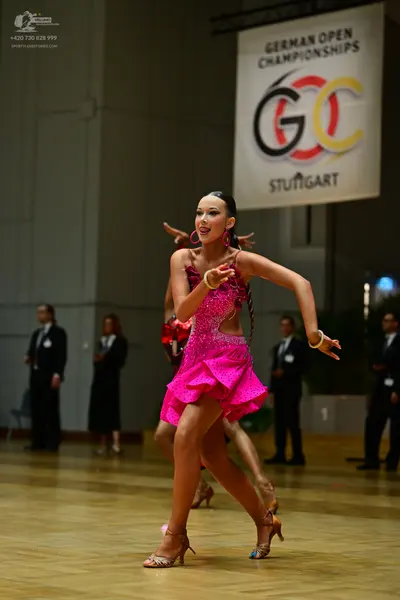 Dancesport competitor: Female dancer: bright pink sequined Latin dance dress with cutouts, paired with 
