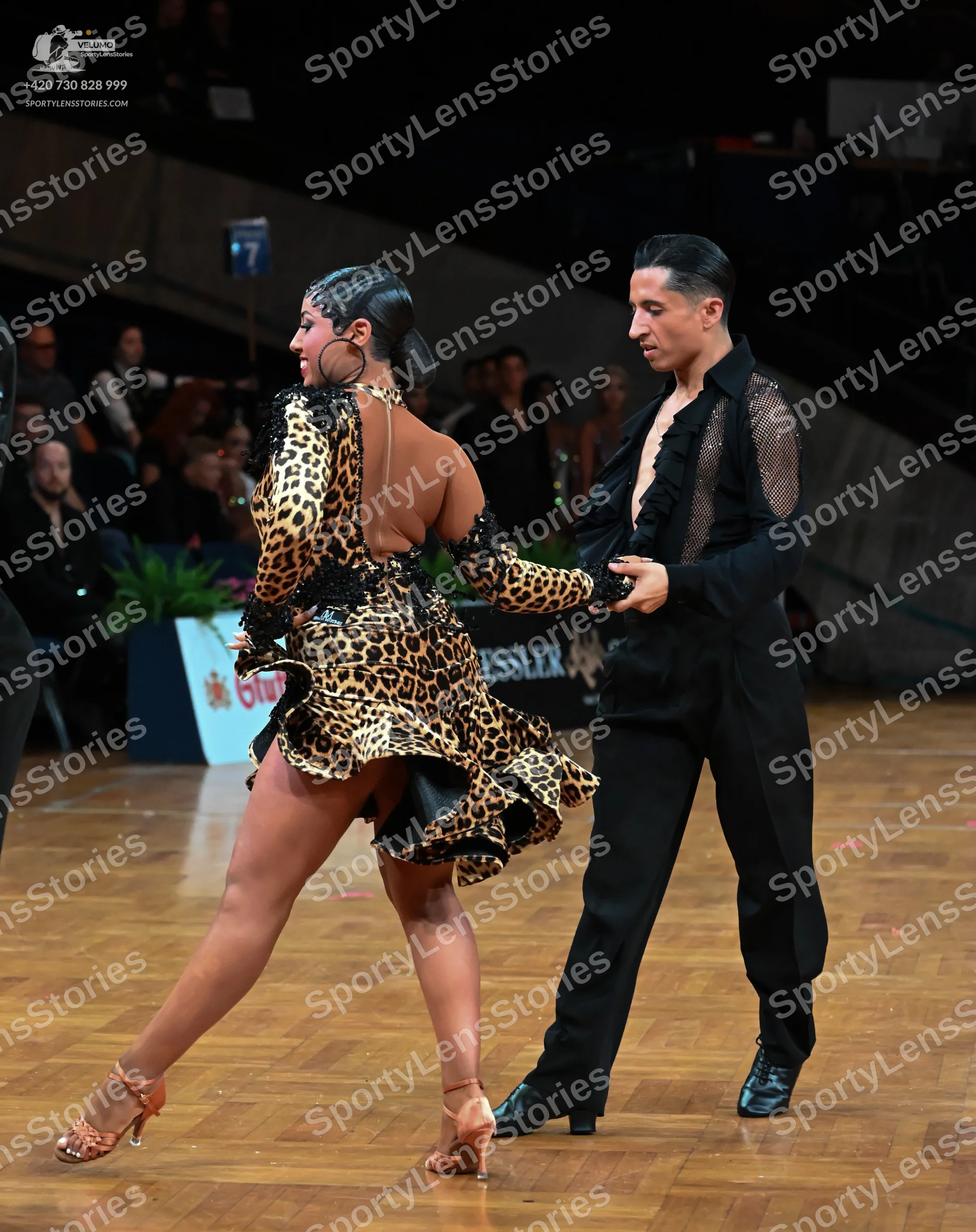 Dancesport competitor: Female dancer: leopard print latin dress with a flared skirt, large hoop earring