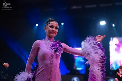 Dancesport competitor: Female dancer: lilac Latin dance dress with sequins, long sleeves, feathery trim
