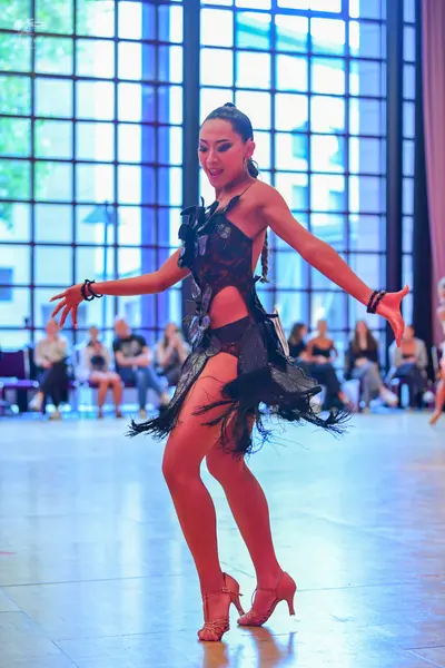 Dancesport competitor: Female dancer: black Latin dance dress with fringe/textured trim and black brace