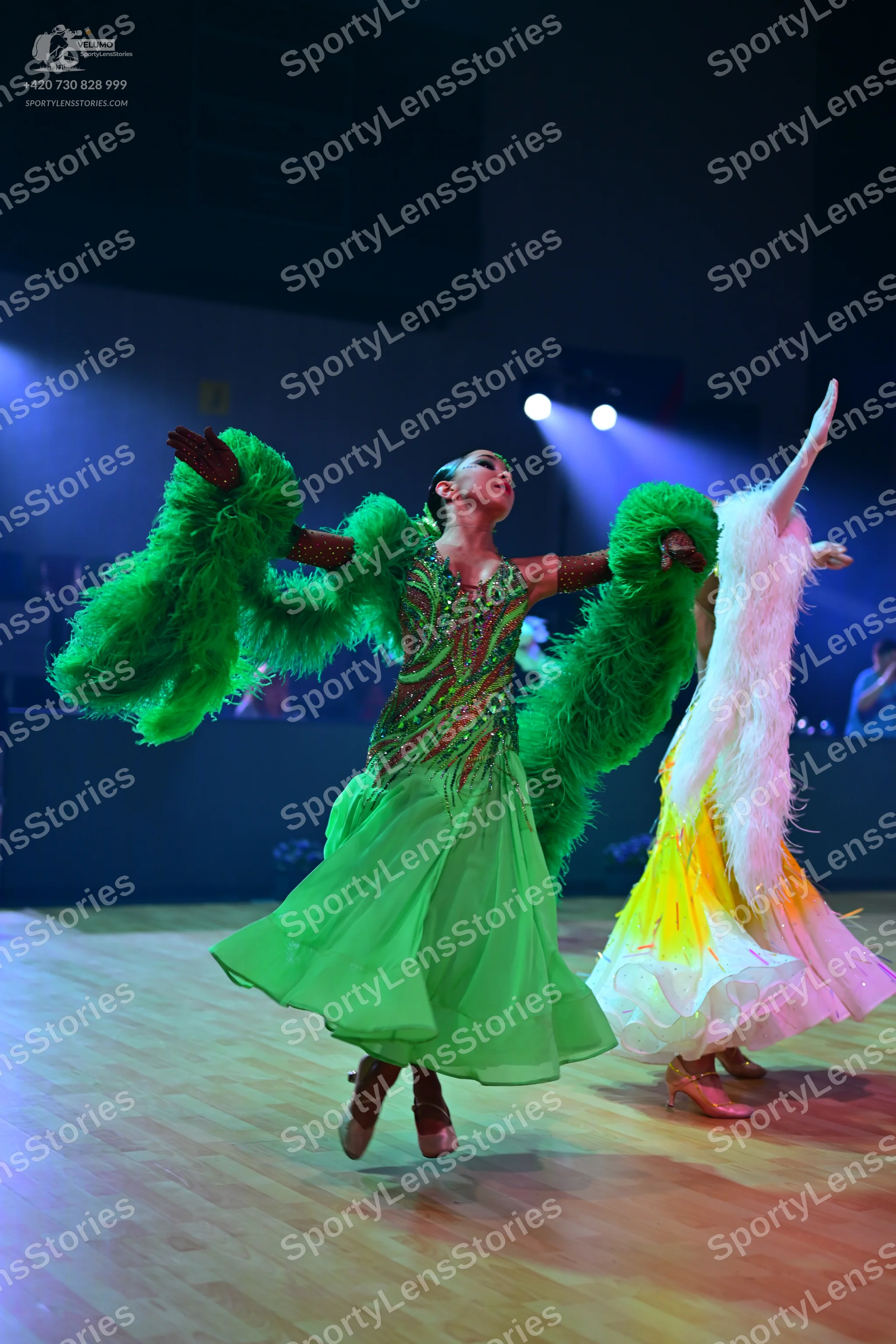 Dancesport competitor: Female dancer in foreground: bright green ballroom dress with a sequined bodice
