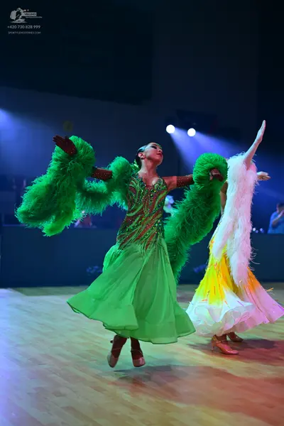 Dancesport competitor: Female dancer in foreground: bright green ballroom dress with a sequined bodice 