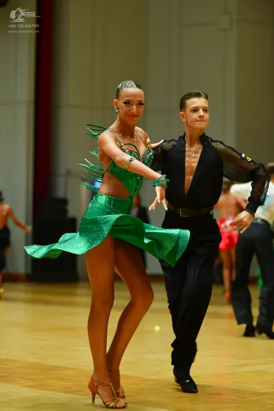Dancesport competitor: Female dancer: green sequined latin dress with fringe-like accents, green earrin