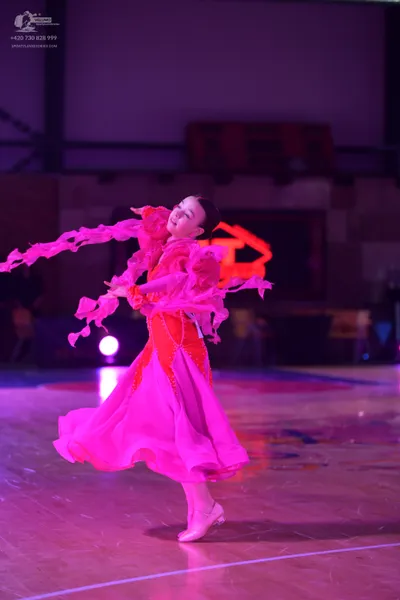 Dancesport competitor: Female dancer: bright pink ballroom dress with a voluminous, flowing skirt and l