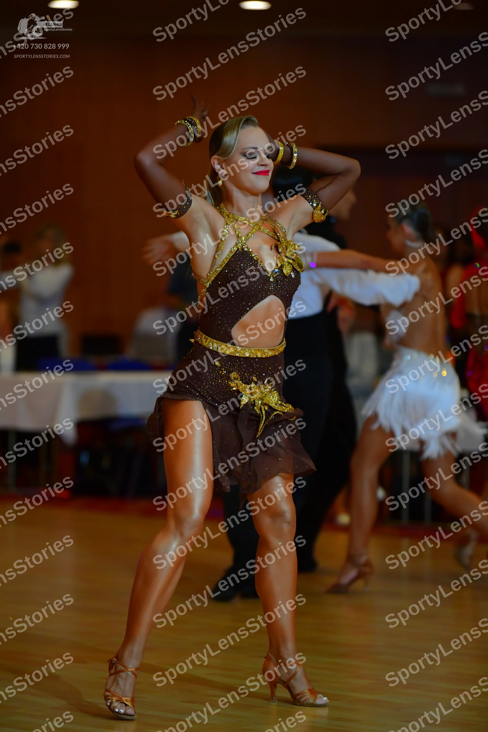 Dancesport competitor: Female dancer (center): brown latin dress with gold sequin/bead embellishments a
