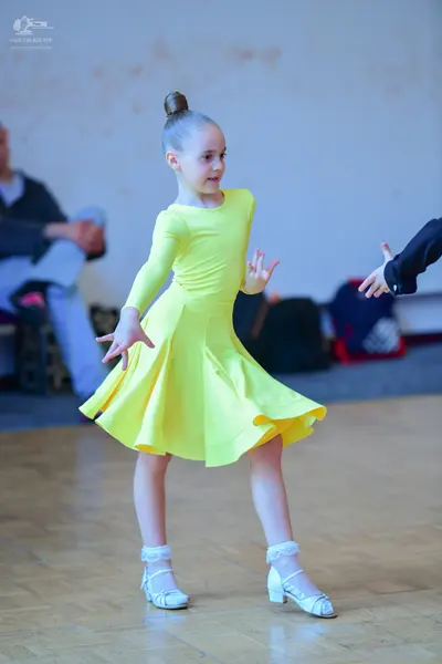 Dancesport competitor: Female dancer: yellow long-sleeved dress with a flared skirt and white dance sho