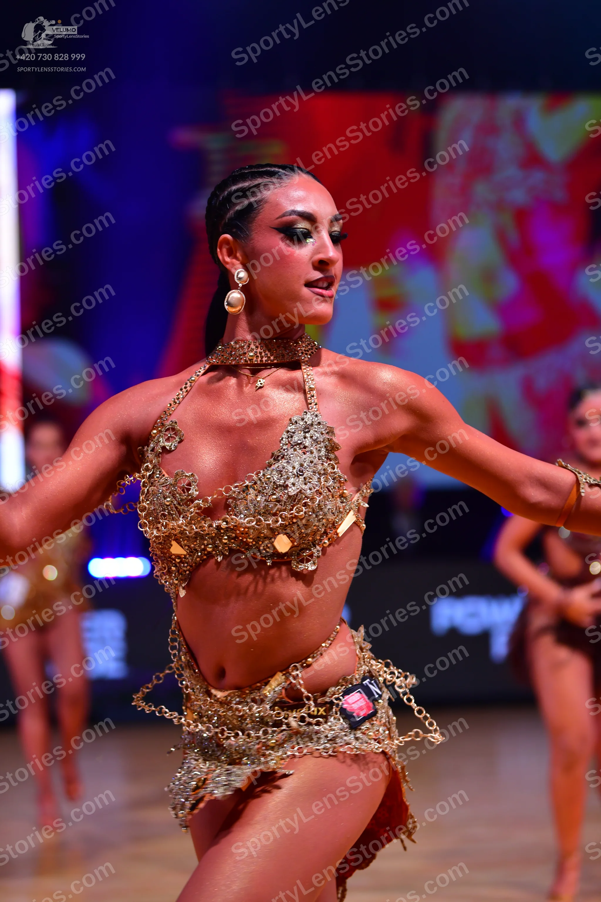 Dancesport competitor: Main female dancer: gold Latin costume with heavy sequin and metallic embellishm