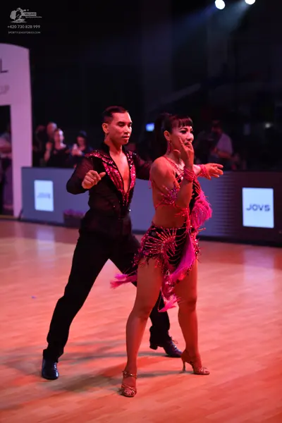 Dancesport competitor: Male dancer: black long-sleeved shirt with pink sequin embellishments and black 
