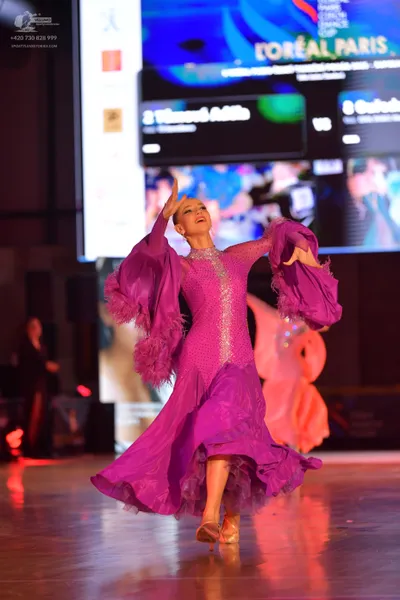 Dancesport competitor: Female dancer: purple ballroom dress with a sequined bodice and voluminous, ruff